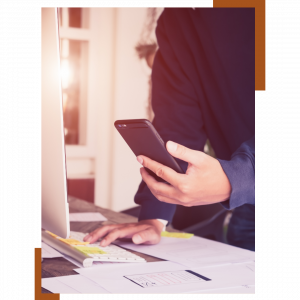 Le blog marketing digital, Photo d'un homme qui tient un smartphone devant son ordinateur, pour article de blog : Stratégies social medias pour les petites entreprises