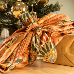 Photo zoomée d'un cadeau emballé façon Furoshiki sous un sapin de Noël